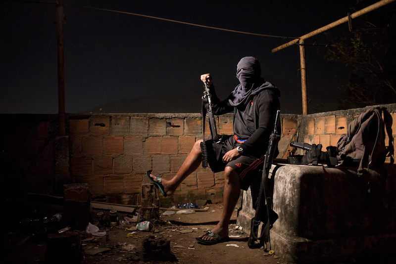 “A drug gang leader poses for a photo in a slum in Rio de Janeiro, Brazil. He told Associated Press journalists that drug dealers win the hearts and minds of locals by paying for food and medicine, providing a lifeline for many living in crushing poverty.”